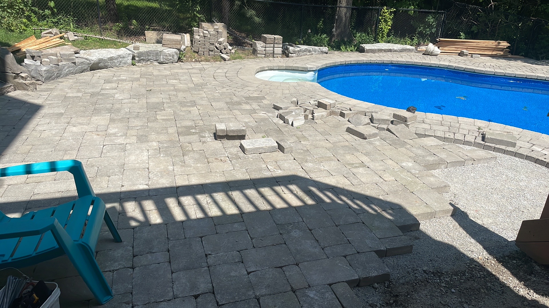 Curved interlocking paver pool deck being installed around a kidney-shaped pool